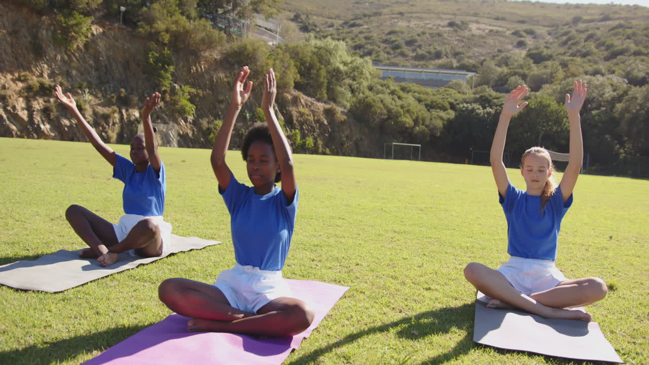 Practicing yoga on mats, girls in school uniforms meditating outdoors