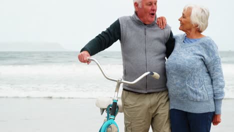 Happy-senior-couple-standing-with-their-bicycle