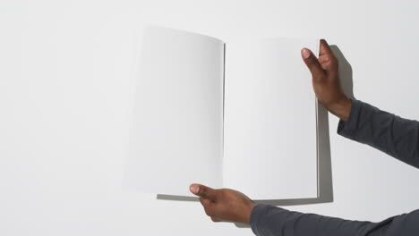 video of hand of african american man holding book with blank pages, copy space on white background