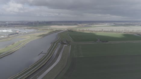Drone-shot-of-typical-Dutch-landscape-with-flat-farmland,-a-river-and-windmills