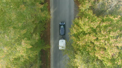 一輛有拖車的汽車在樹林路上駕駛的空中景色