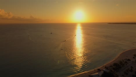 aerial sunset descent paints seven mile beach orange as boats cross shimmering caribbean