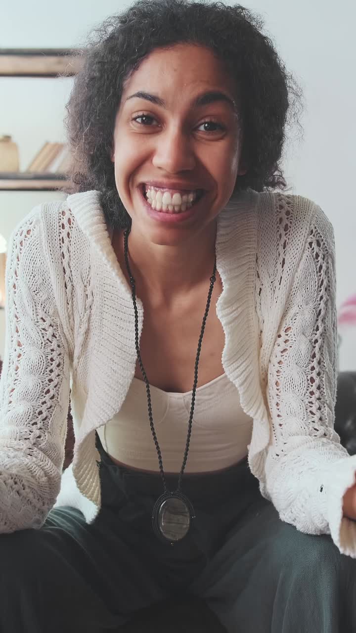 Young beautiful positive african american woman talks with smile and waves hand