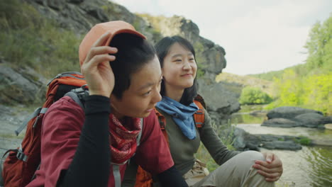 asian female hikers talking on river bank