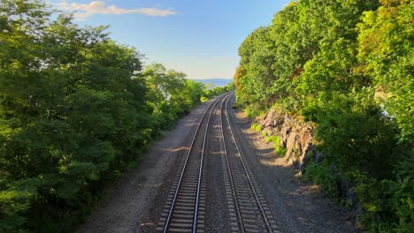Aerial drone footage of the metro north Hudson Line train tracks during summer next to the Hudson river between beacon and cold spring, new york, usa
