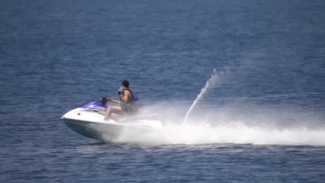 man riding jetski in mediterranean sea jumping over water in slow motion action shot