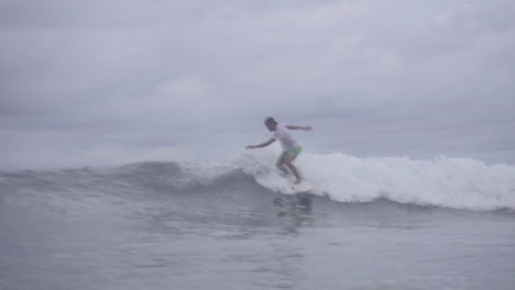 surfistas filipinos asiáticos disfrutando de pequeñas olas en un clima sombrío