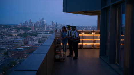 people on a rooftop balcony overlooking a city skyline at dusk