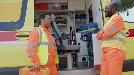 Two-Medical-Assistants-Talking-In-Front-Of-An-Ambulance