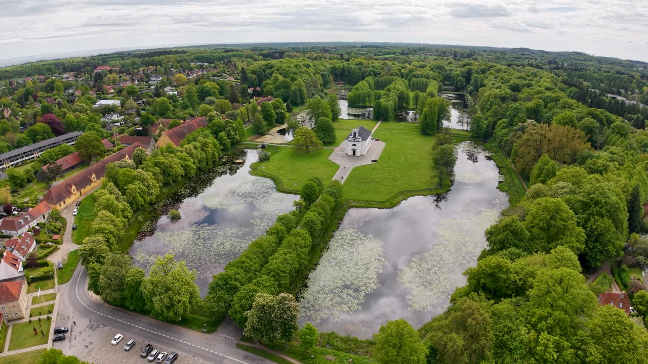 Drone aerial footage capturing geometric rectangular ponds and water channels surrounded by lush green countryside and trees in Denmark