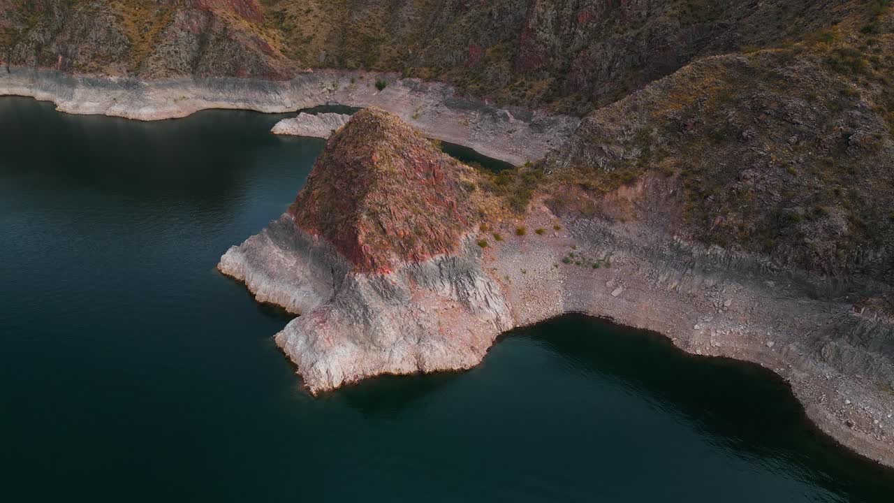 Avvicinamento aereo a una penisola rocciosa e alle acque turchesi del bacino idrico a Dique Los Reyunos, Mendoza, Argentina.