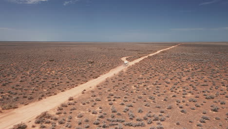 Aerial-view-following-a-RV,-driving-on-a-dusty-desert-road-sunny-day,-in-Australia---tracking,-drone-shot