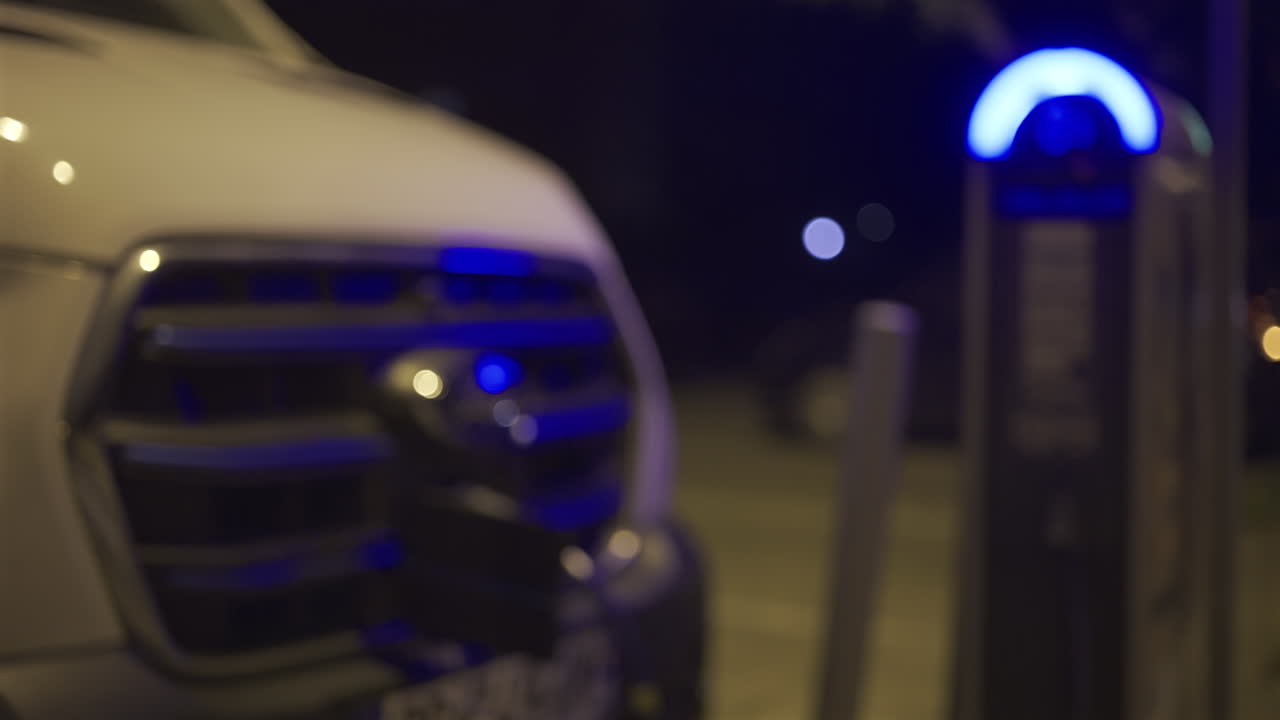 Blurred view of a white car charging at a station in the evening