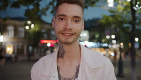 smiling man with tattoos on a city street at night