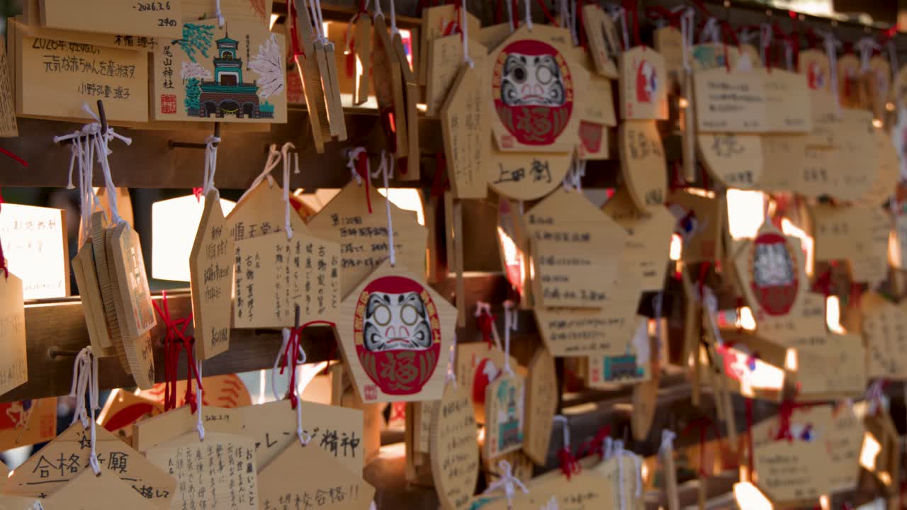 日本の神社の境内に吊るされた伝統的な木製絵馬のクローズアップトラッキングショット
