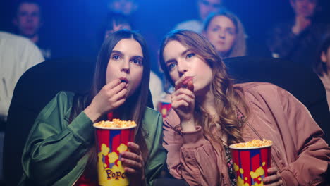 mujeres jóvenes comiendo bocadillos en el cine