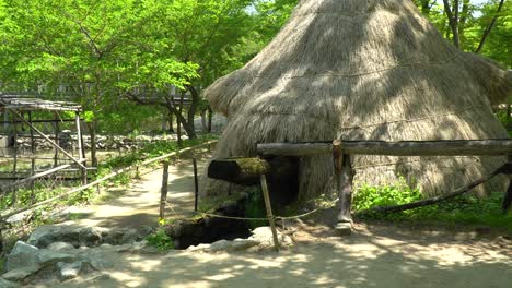 Water-flowing-through-open-wooden-pipes-filling-old-decrepit-wooden-water-mill-for-milling-wheat-and-rice-in-Korean-folk-village-Yongin-City---full-shot