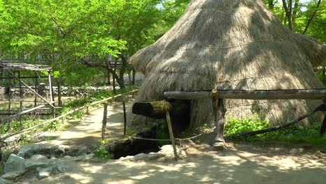 한국 민속촌 용인시의 밀과 쌀을 제분하기 위한 오래된 낡은 나무 물레방앗간을 채우는 열린 나무 파이프를 통해 흐르는 물 - 전체 샷