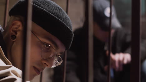 young man behind metal bars