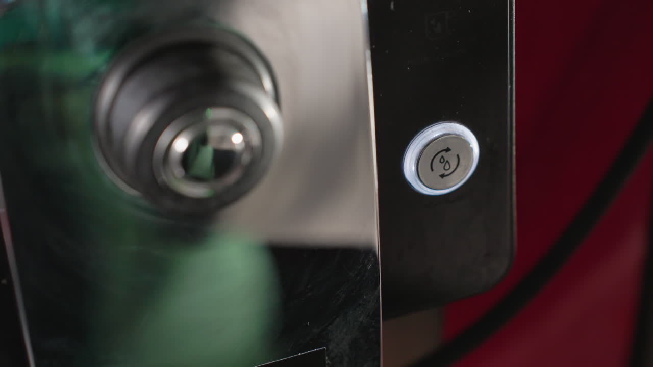 Close-up of espresso machine nozzle positioned above an empty paper cup. The machine is about to dispense liquid, showcasing the precise action of the espresso-making process in a caf setting