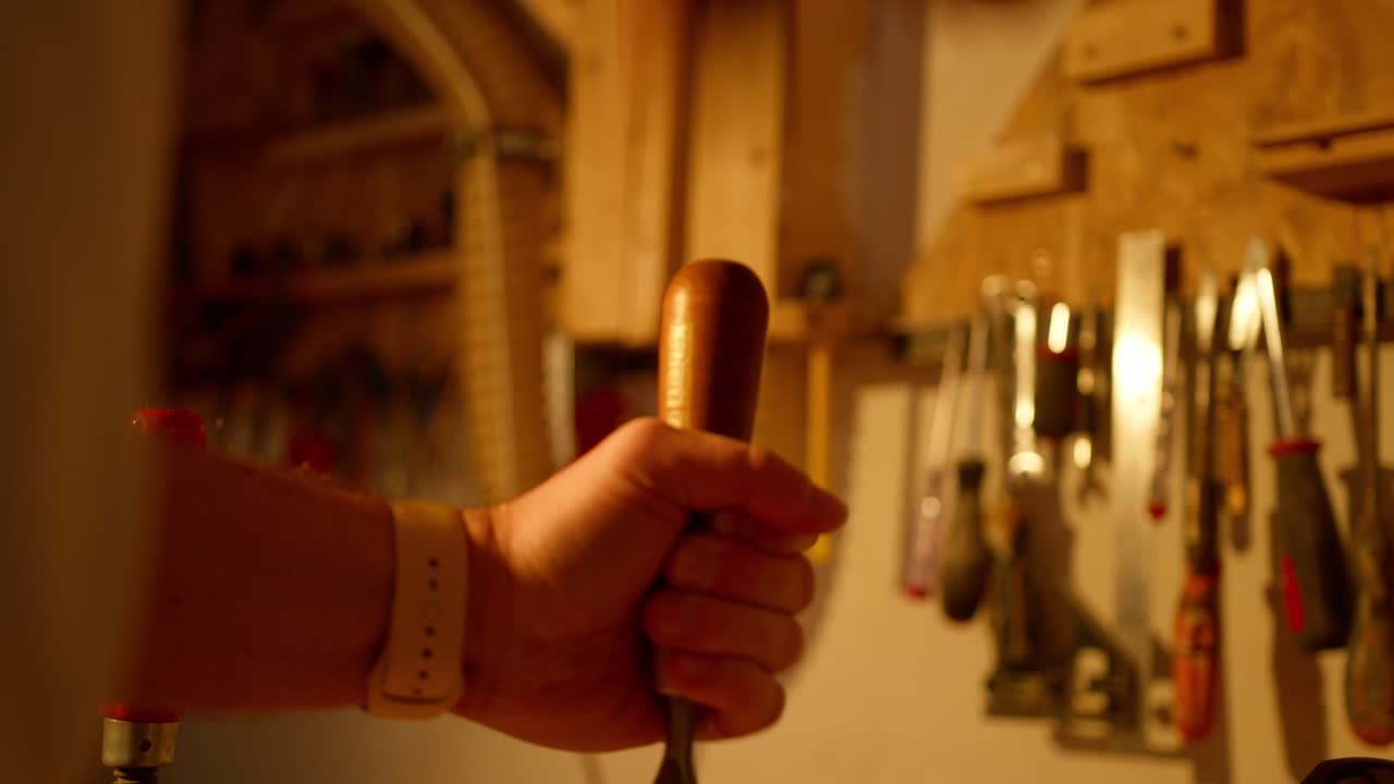 primer plano de un hombre martillando un objeto para abrir una tabla de madera en pedazos