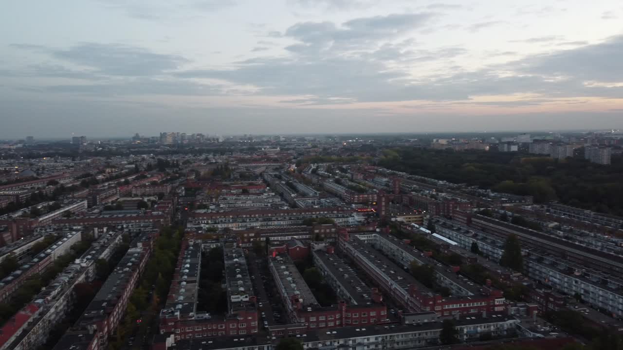 Beautiful rooftops over the parallel gray buildings in Amsterdam's neighborhoods in the sunset light, aerial view
