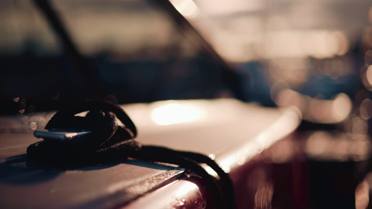Close up of a boat deck during sunset, with a focus on a black rope coiled on the surface