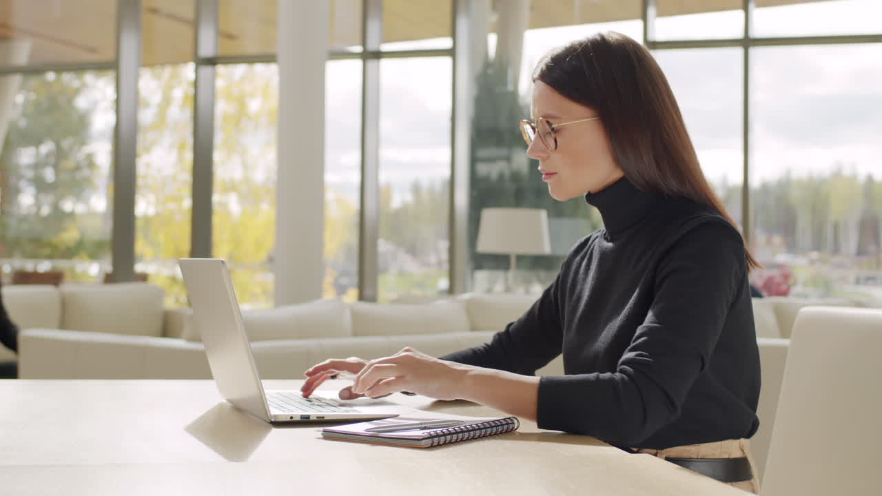 Woman working on laptop and taking notes in a modern office