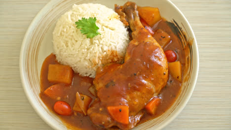 homemade chicken stew with tomatoes, onions, carrot and potatoes on plate with rice