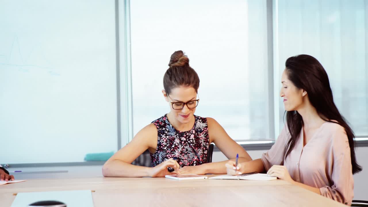 mujeres ejecutivas discutiendo sobre una tableta digital