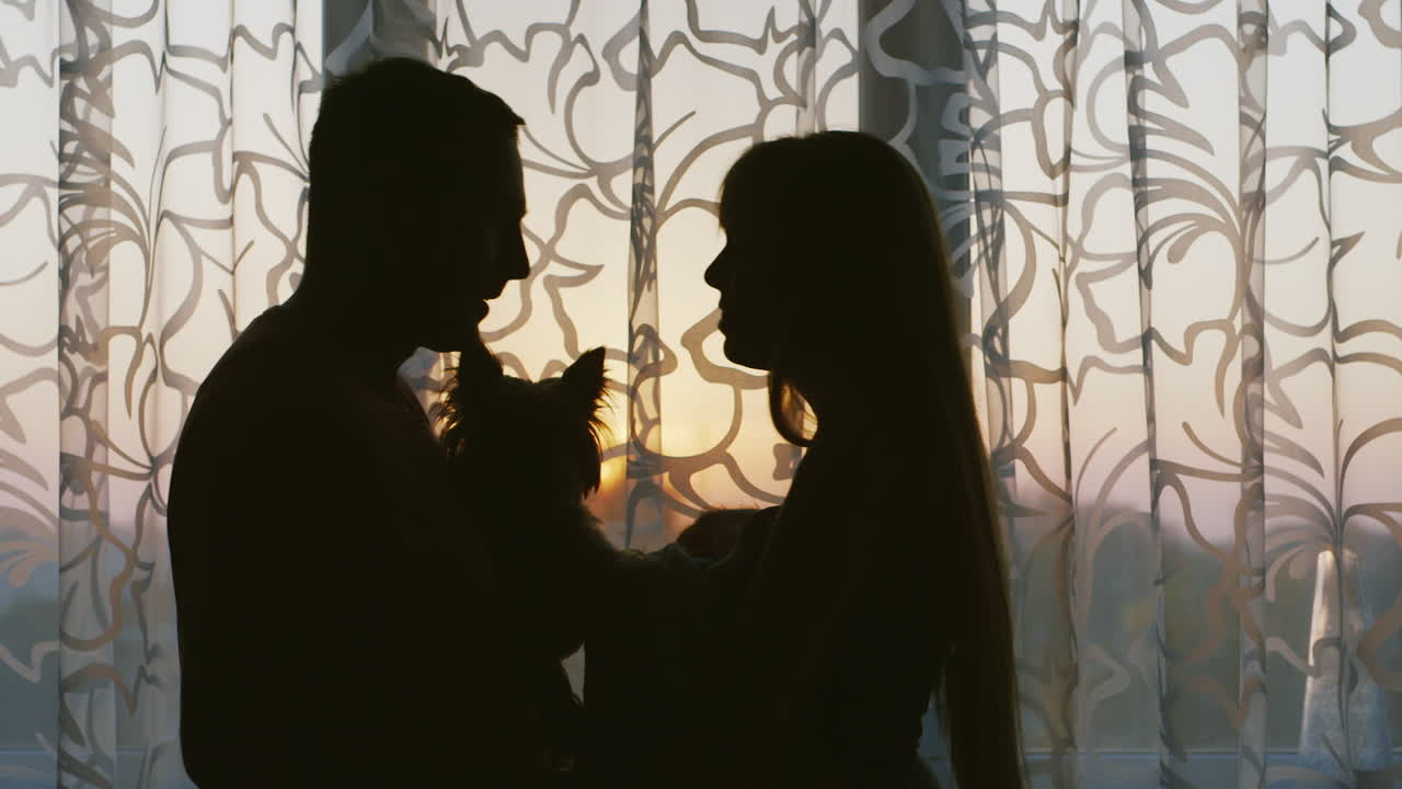 엄마에게 키스하는 창문 근처에 서 있는 행복하고 사랑스러운 부부는 아기 아빠의 손에