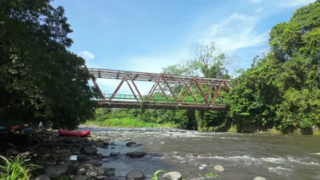 rafting on a river with a metal bridge