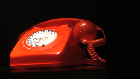 receiver falling onto red dial phone on black background