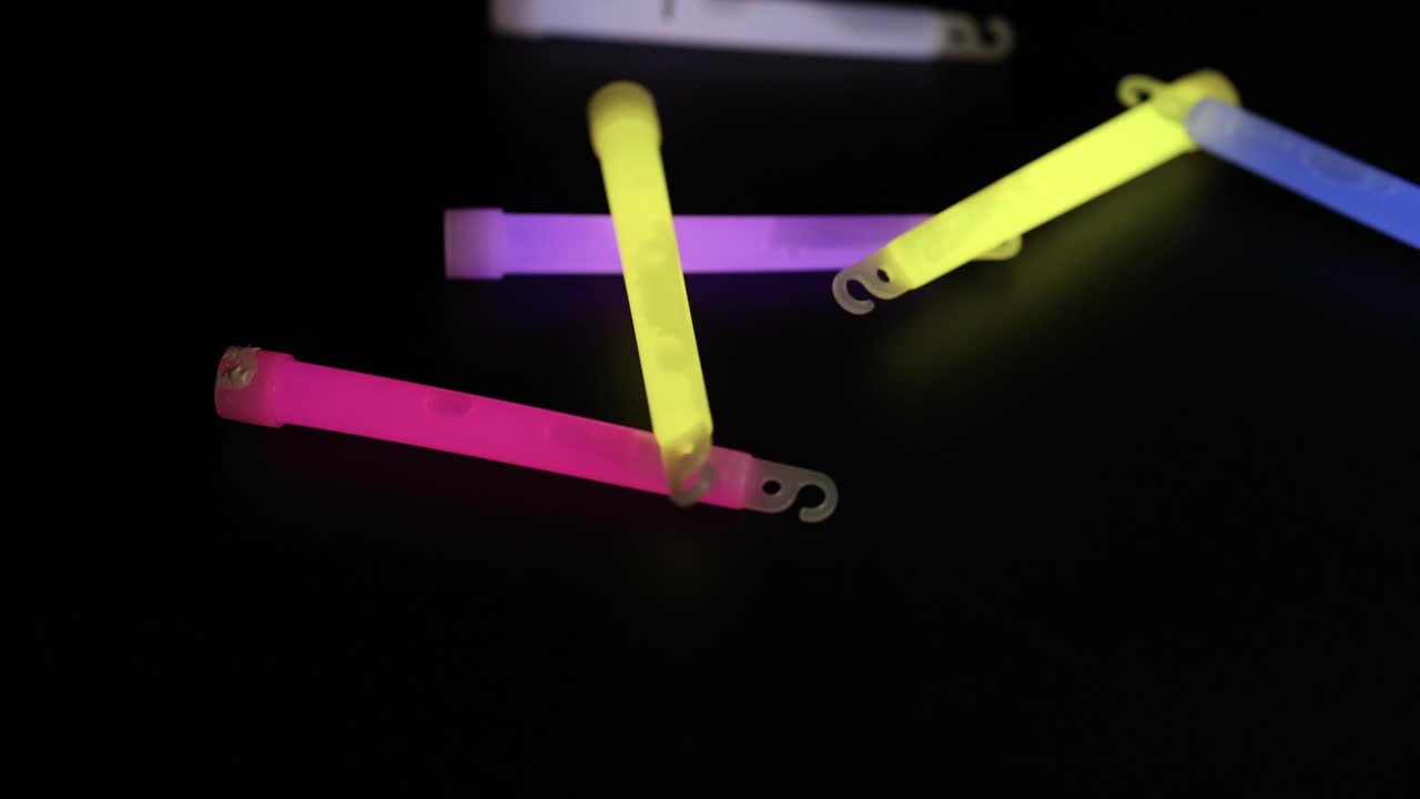 Glow sticks falling and scattering on a dark surface