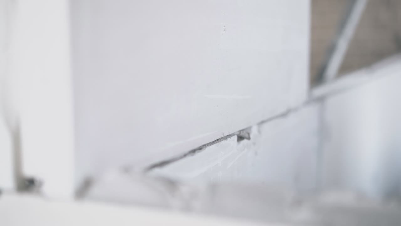 worker holds gypsum pasteboard and puts on grey substance