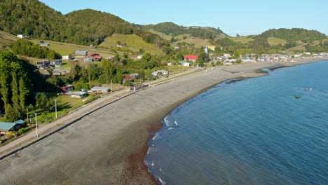 aerial shot of tenaun beach in chiloé with lush green hills and a curving shoreline