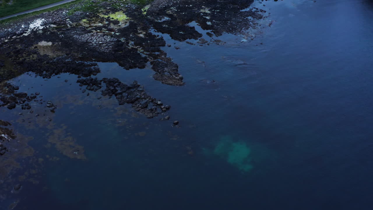 Slow birdseye shot of empty Giant's Causeway and Atlantic Ocean during evening
