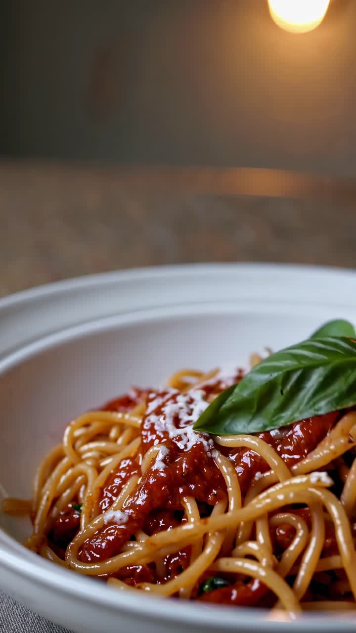 Video ravvicinato di spaghetti al pomodoro e basilico, ripreso da un angolo laterale