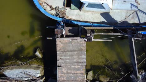 un viejo muelle en una costa rocosa con un barco antiguo atado a él - vista aérea de pájaro directamente hacia abajo