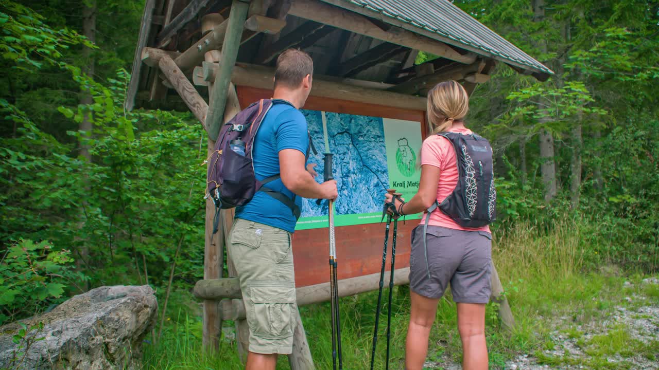 Man and woman having a look a the map. Pointing to a place of interest. Hiking adventure Topla Valley, Slovenia