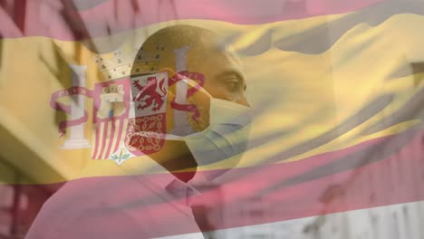 animation of flag of spain waving over man wearing face mask during covid 19 pandemic