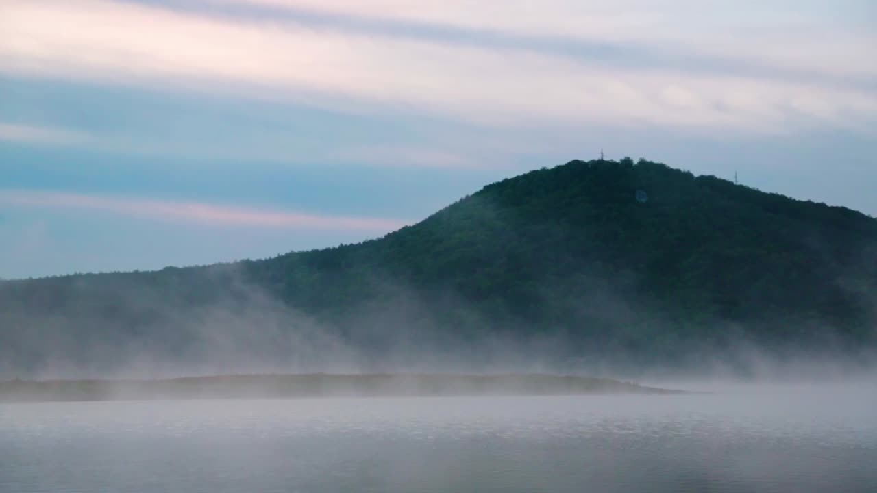 Fog on a reflective lake in the mountains at sunrise