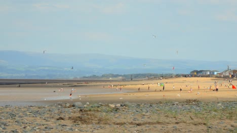 Pools-of-sunshine-racing-across-beach-and-hills-in-distance-with-people-moving