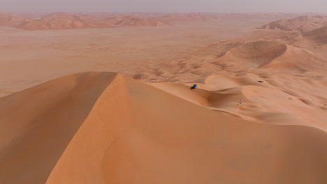 aerial shot of the highest dune in the empty quarters, oman, with a lone vehicle