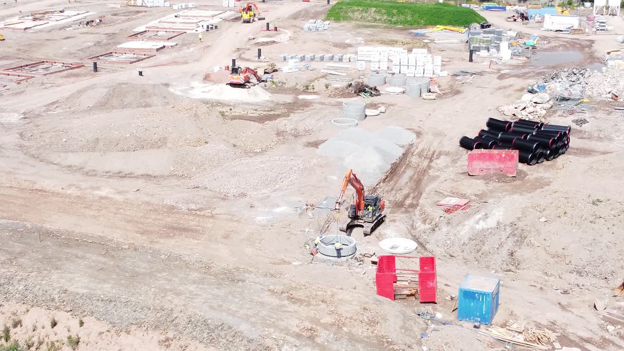 vehículo excavadora de excavación que prepara la vista aérea de la tubería de cemento en el sitio de construcción del desarrollo de viviendas
