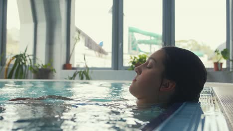 a young woman is seen in a pool, relaxing after a swim