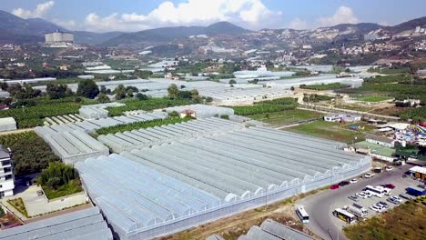 aerial view of large greenhouse complex with mountains and city in the background