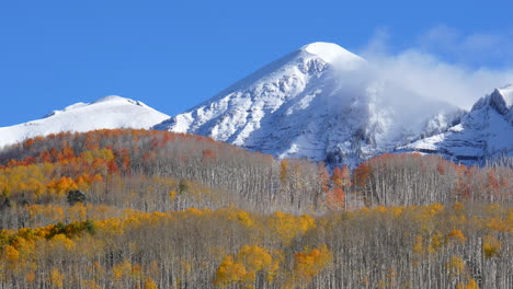 frosted crisp cold frozen morning kebler pass colorado cinematic fall winter season collide first white snow red yellow orange aspen tree forest clouds blue sky rocky mountain peak stunning slight pan