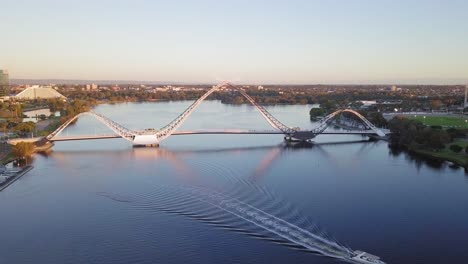 vista aérea de uma ponte matagarup em perth, austrália ocidental com barco atravessando ondas no rio cisne