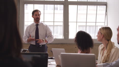 Middle-aged-businessman-stands-talking-at-meeting,-close-up